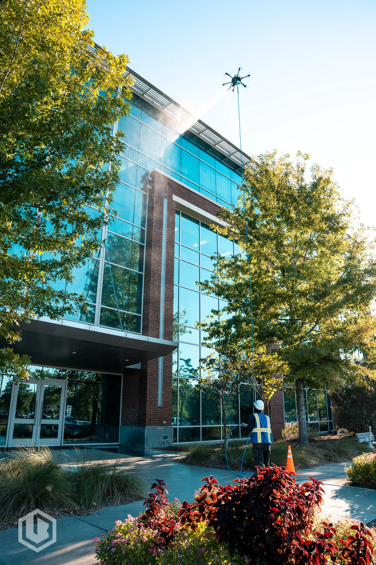 Cleaning drone spraying a glass-fronted commercial building exterior